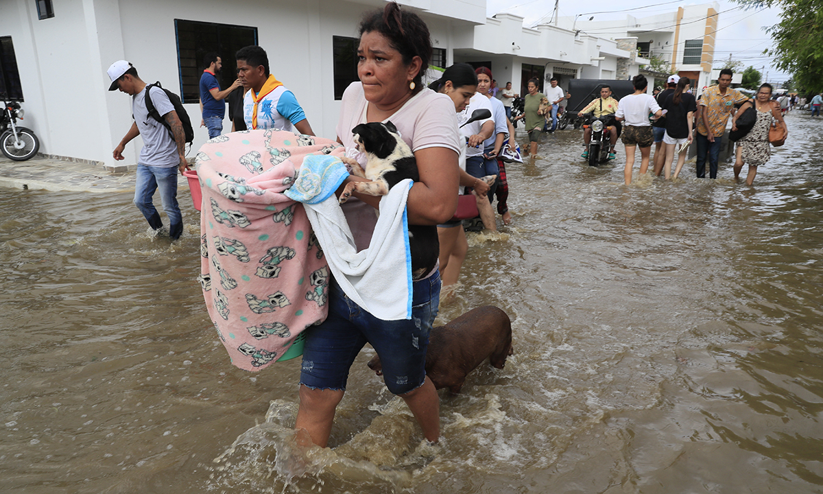 지난 7일(현지시간) 집중호우로 콜롬비아 몬테리아 인근 시누강이 범람하면서 주민들이 가재도구를 건지기 위해 애쓰고 있다. 온실가스 배출이 늘면 자연재해도 늘어날 것이란 전망이 나온다. 몬테리아=EPA연합뉴스