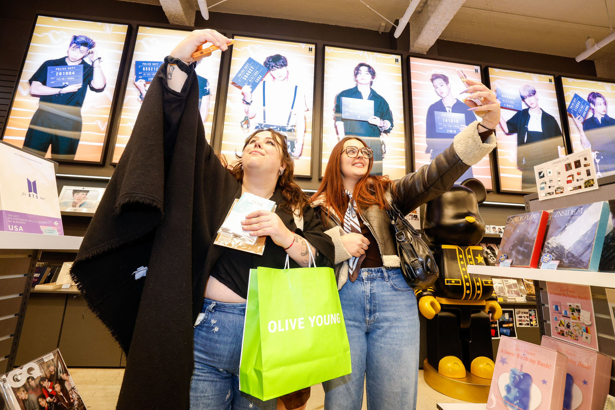 방탄소년단(BTS) 컴백 공연을 앞둔 19일 서울 중구 명동의 K팝 특화 매장에서 프랑스인 ‘아미’(BTS 팬덤명)가 BTS 멤버들 사진을 배경으로 기념사진을 찍고 있다.유희태 기자