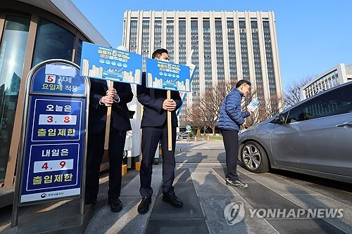 25일 서울 종로구 정부서울청사 입구에서 청사관리소 관계자들이 승용차 5부제 동참 캠페인을 하고 있다.