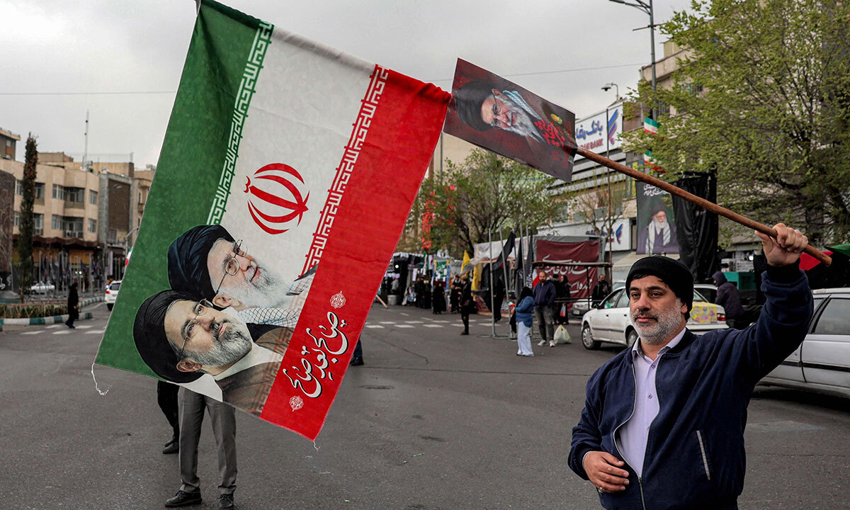 이란 테헤란에서 25일 한 시민이 최고지도자 알레 하메네이와 그의 후임인 모즈타바 하메네이의 모습이 담긴 국기를 흔들고 있다. AFP연합뉴스