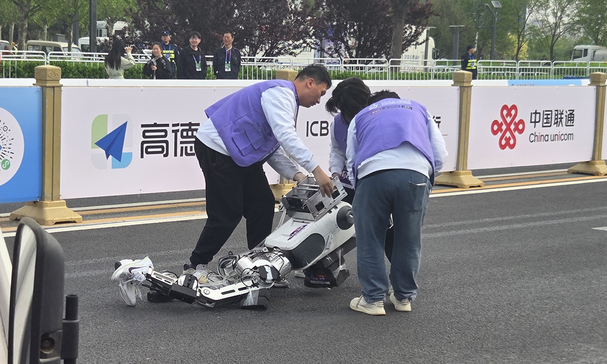 휴머노이드 로봇이 출발지점에서 달리다 넘어져 관계자들이 로봇을 들어올리고 있다. 뉴시스