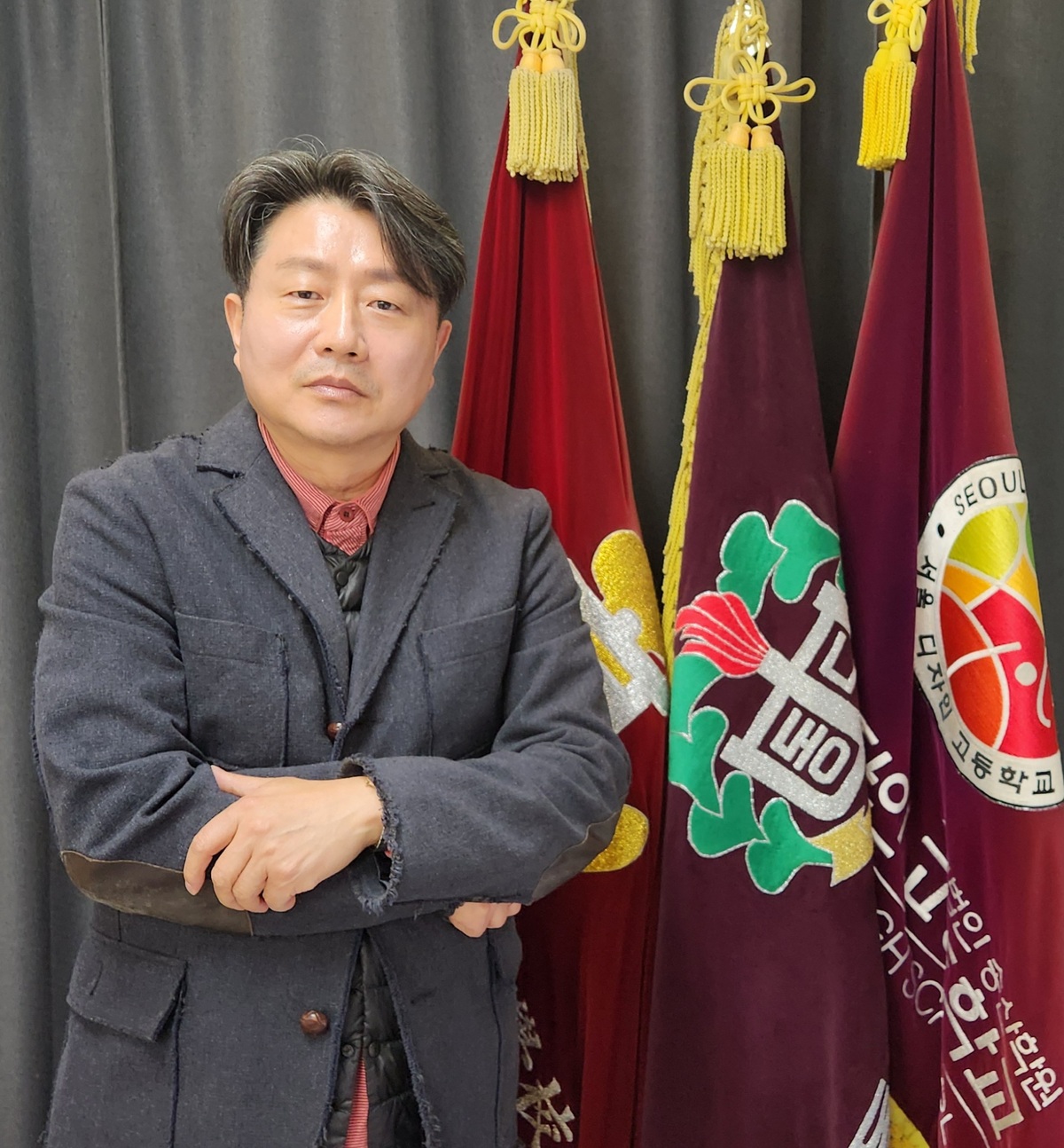 이정목 서울디자인고 교장이 교기 앞에서 포즈를 취하고 있다. 김청중 논설위원