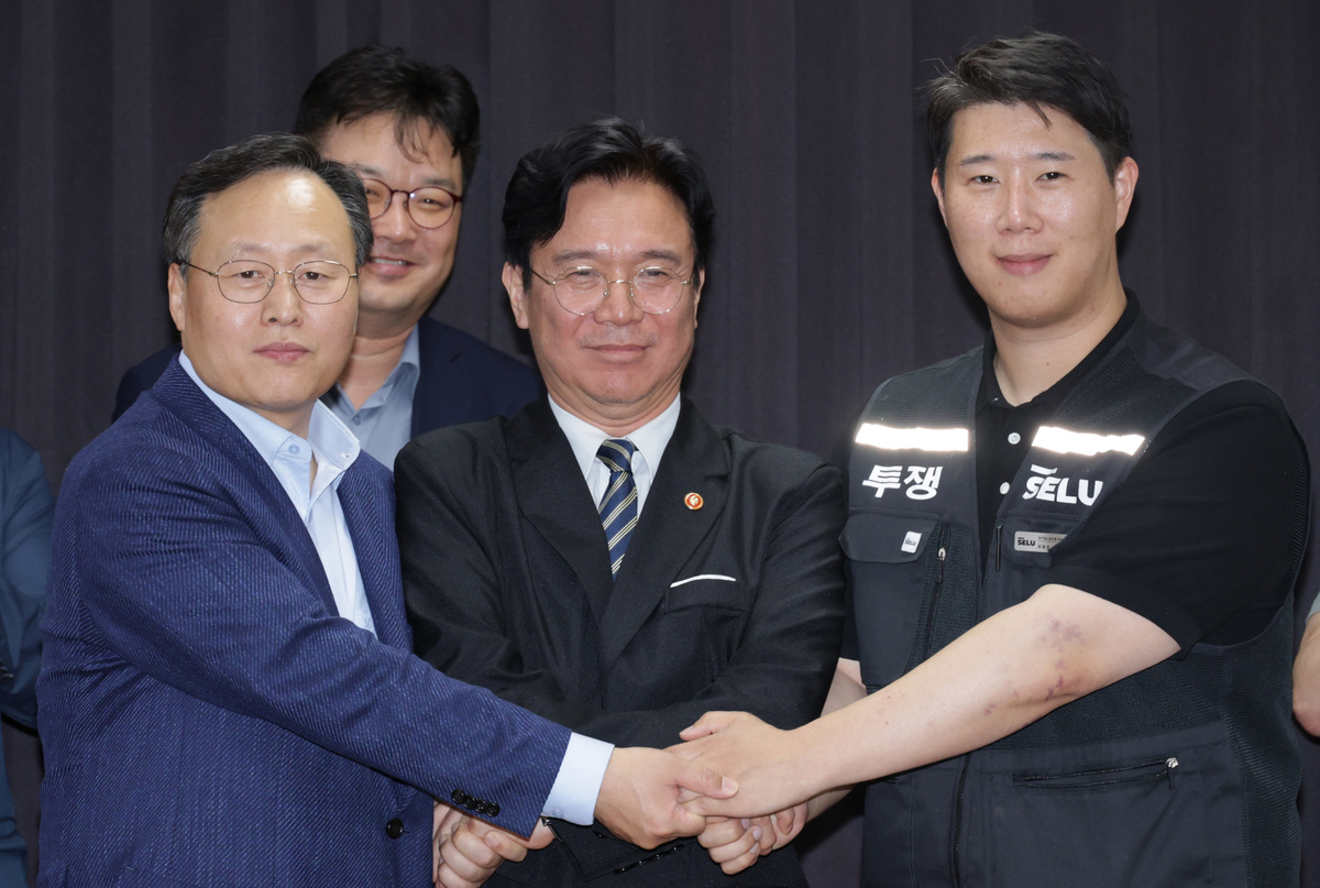 20일 경기도 수원시 장안구 경기고용노동청에서 열린 삼성전자 임금협상을 마친 후 여명구 삼성전자 DS(디바이스솔루션·반도체 사업 담당) 피플팀장과 김영훈 고용노동부 장관, 최승호 삼성그룹 초기업노동조합 삼성전자지부 위원장이 잠정 합의한에 서명한 후 손을 맞잡고 있다. 뉴스1