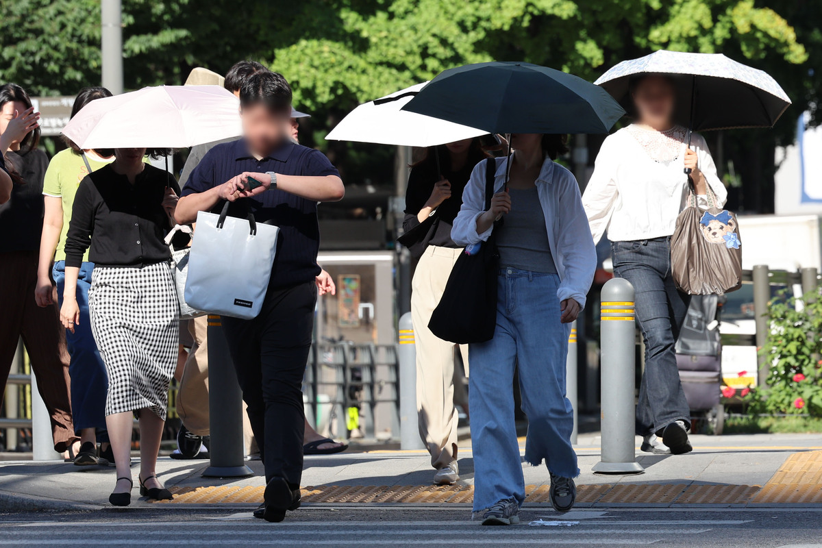 지난 12일 오전 서울 종로구 광화문역 인근에서 시민들이 양산을 쓴채 출근하고 있다. 뉴시스