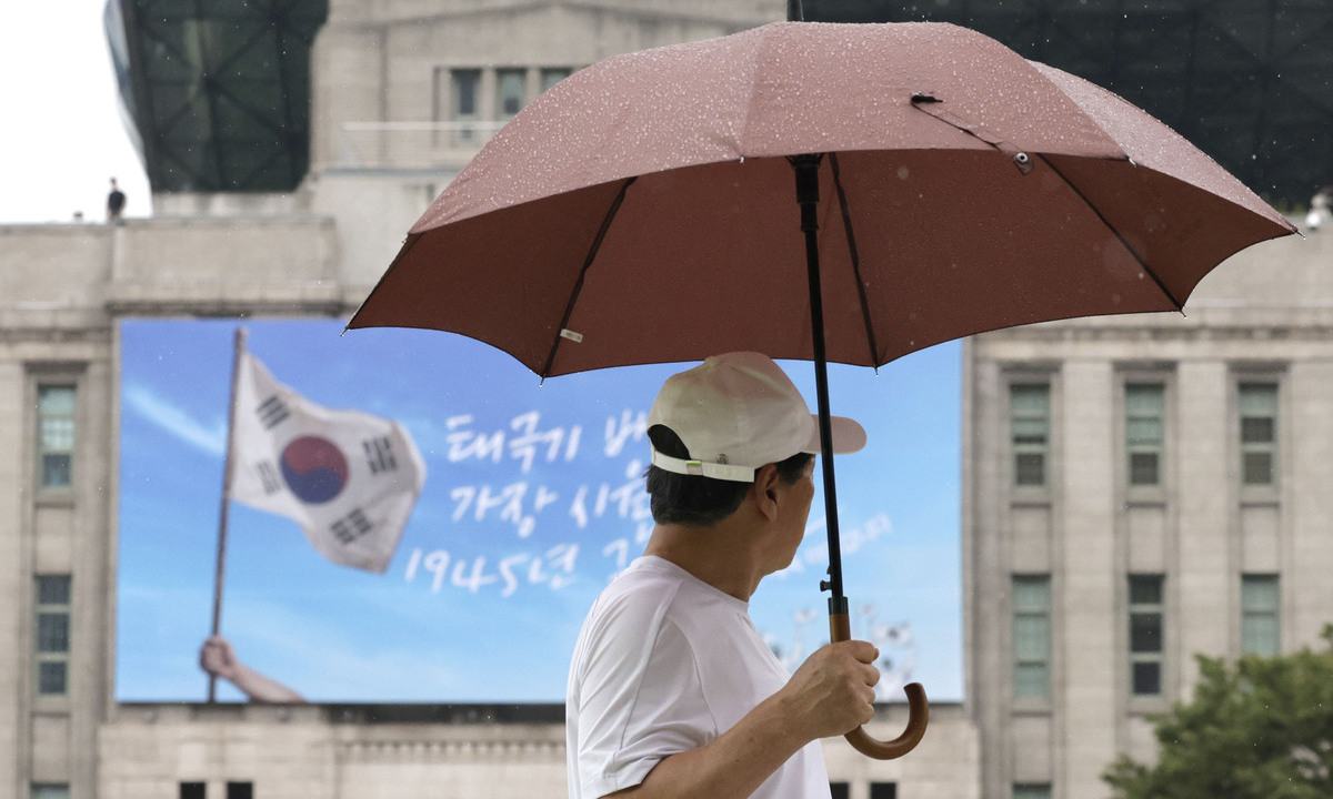 광복절 연휴가 시작된 15일 서울 중구 서울시청 앞에서 시민이 우산을 쓰고 길을 걷고 있다.