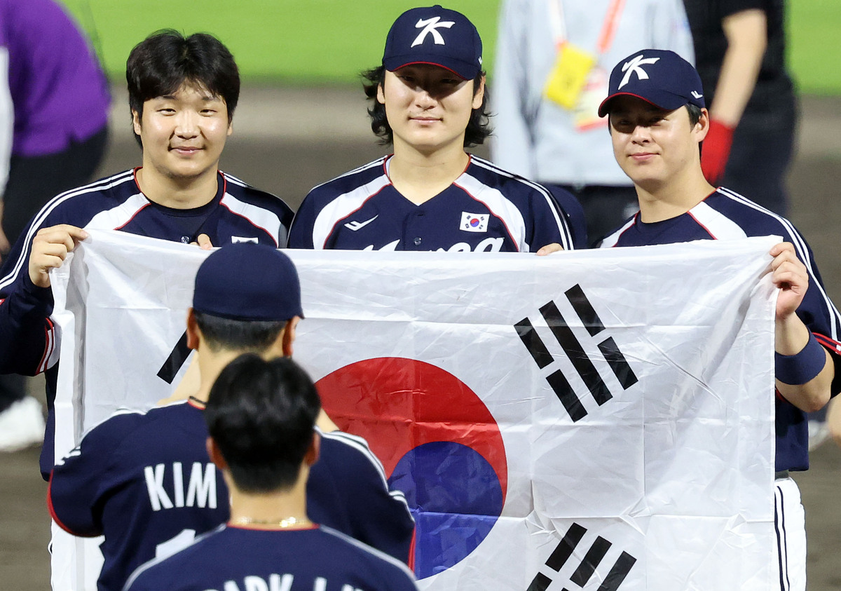 27일 오후(현지 시간) 일본 아이치현 도요하시 시민구장에서 열린 2026 아이치·나고야 아시안게임 야구 결승전 한국과 일본의 경기, 3-1로 승리하며 금메달을 획득한 한국 문보경, 곽빈, 노시환이 태극기를 들고 기념촬영을 하고 있다. 뉴시스