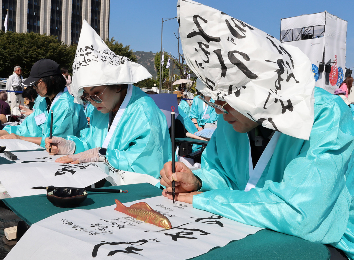 한글날인 9일 서울 광화문광장에서 한글날 제정 100주년을 기념해 ‘한글, 세상을 열다’라는 주제로 휘호대회가 열린 가운데 시민들과 외국인 관광객들이 붓글씨를 쓰고 있다. 이번 대회는 조선시대 과거시험을 재현하는 의미로 참가자 전원이 두루마기 차림으로 한글 휘호를 했다./2026.10.09./이재문 기자