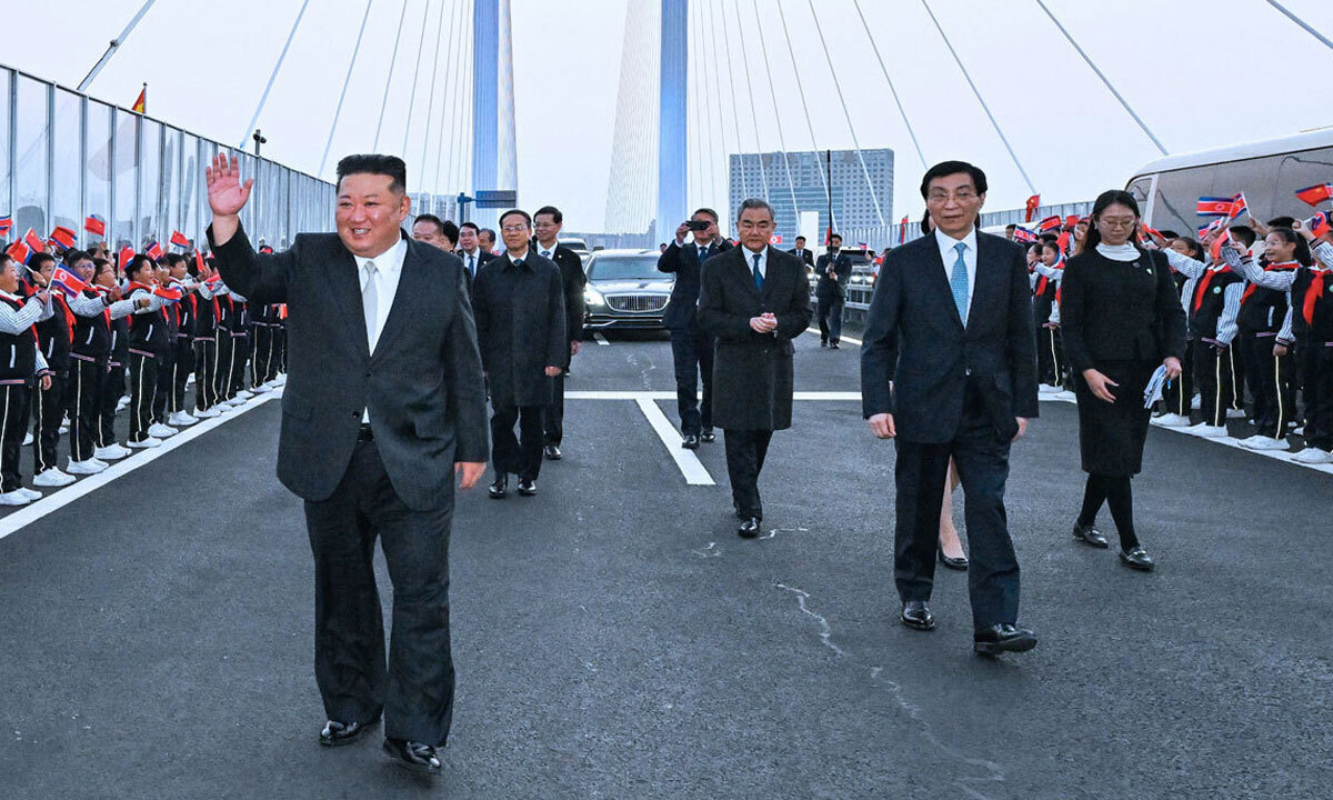 김정은 북한 국무위원장(왼쪽)이 24일 단둥 방문을 마친 뒤 북한 평안북도 신의주와 연결되는 신압록강대교에서 환송 인파에 화답하며 걷고 있다. 왕후닝 중국 전국인민정치협상회의 주석과 왕이 외교부장&nbsp;등이 배웅했다.&nbsp;단둥=신화연합